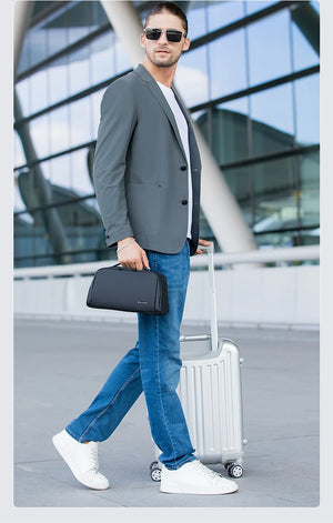 Black waterproof toiletry bag with top handle and zip closure, carried by a model.
