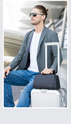 Black toiletry bag with handle and zipper front placed beside luggage on a traveler.