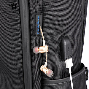Close-up of headphone connection cable and USB port area on a grey backpack.