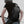 Black sling bag worn across back with front pocket and adjustable shoulder strap