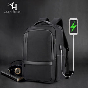 Grey waterproof travel backpack with USB charging cable connected to a phone.