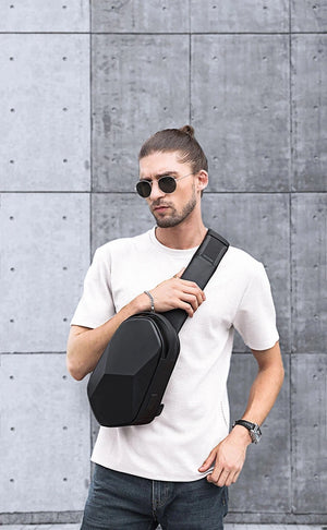 Black compact crossbody bag worn crossbody with adjustable strap on a person