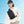 Black compact crossbody bag worn on shoulder with adjustable strap and front zip pocket