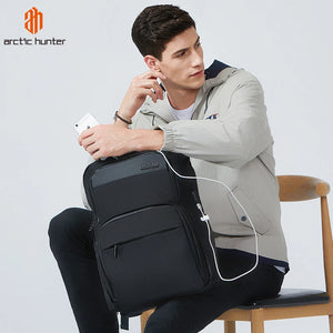 Black travel backpack worn by a person, with white charging cable connected