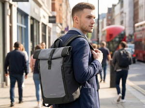 Man walking on a city street with a grey roll-top backpack