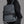 Dark gray travel backpack with front zip pocket and padded shoulder straps, side view