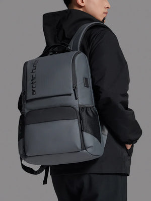 Dark gray travel backpack with front zip pocket and padded shoulder straps, side view
