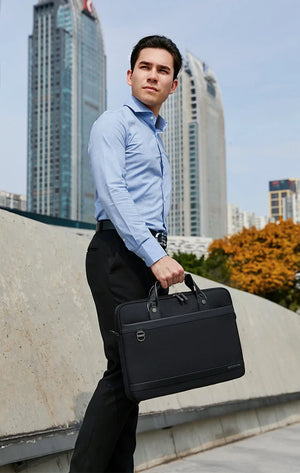 Black laptop bag carried by man with top handle and shoulder strap