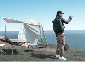 Grey roll-top waterproof backpack on person, front flap and rolled top closure visible