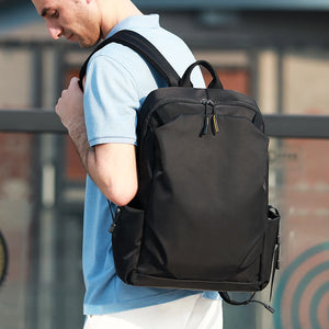 Black backpack worn on shoulders with top handle and dual front zipper pulls