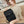 Black compact commuter backpack with front flap, buckle straps, and top handle