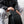 Black crossbody tech bag with front zip pocket, held in hand
