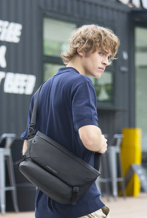 Black crossbody bag side view with front flap and adjustable shoulder strap