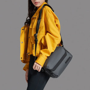 Dark gray crossbody bag worn at the side with adjustable shoulder strap
