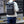 Grey roll-top waterproof backpack on person standing outdoors with shoulder straps