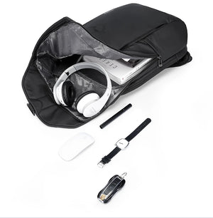 Black roll-top travel backpack with rolled-open top and accessories including headphones