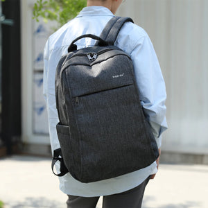 Grey backpack worn on the back with padded straps and front zip pocket