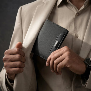 Slim black bifold wallet held in hand, textured exterior and logo tab.