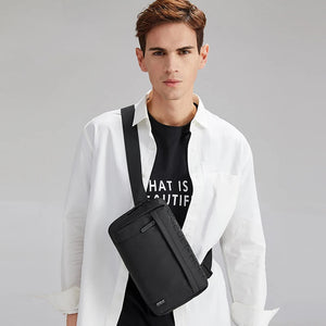 Black crossbody bag worn across chest with adjustable strap and top zipper