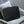 Black padded laptop sleeve with quilted wave pattern, resting on upholstered chair.