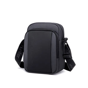 Compact waterproof messenger bag in dark black with front zip pocket and adjustable strap