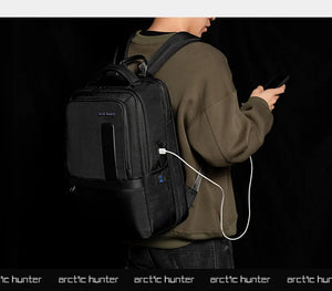 Black waterproof travel backpack being worn with charging cable plugged in