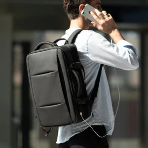 Black backpack worn on back with adjustable shoulder straps and front USB charging cable