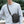 Black small crossbody bag worn with adjustable strap and metal chain-style hardware