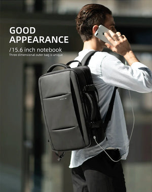 Black backpack worn by a person, front panel visible with attached charging cable