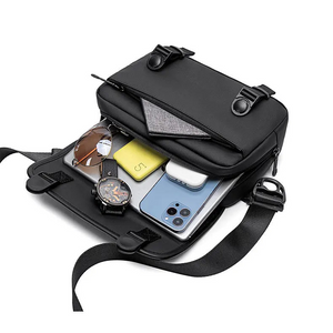 Black cross-body bag open to show inside pockets and small device compartments