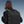 Black travel backpack on a person from back view with secured front buckle straps