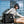 Black waterproof backpack with front flap and shoulder strap, carried outdoors