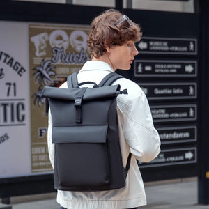 Grey roll-top waterproof backpack worn on back with adjustable shoulder straps