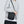 Black compact messenger bag worn crossbody with front logo plate detail