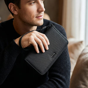 Men's long clutch wallet with wrist strap, dark textured fabric and front zipper pocket