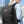 Black commuter backpack with front flap, orange trim, and padded shoulder straps