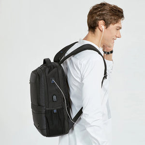 Black travel backpack worn on back with front pocket and charging cable