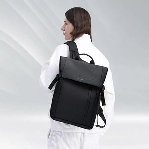 Black backpack worn by a person, featuring a top handle and side carry strap.