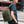 Green commuter backpack worn on back, side view with brown handle accents