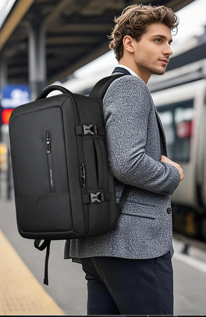 Black travel backpack worn on back with shoulder straps and front zip pocket