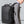 Black travel backpack worn on back with front panel zipper and cross-body strap
