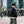 Black travel backpack worn on the back outdoors near buildings, with top handle and shoulder straps