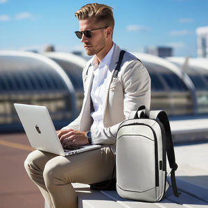Light gray/black travel backpack worn by a person with laptop