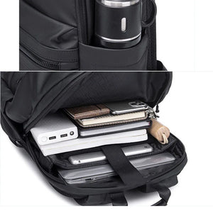 Black backpack with compartments for electronic devices and a coffee mug.