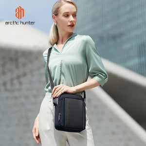 Compact black messenger bag with front pocket and adjustable strap worn on shoulder