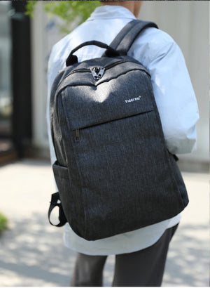 Grey backpack worn by a person with front organizer pocket and top handle