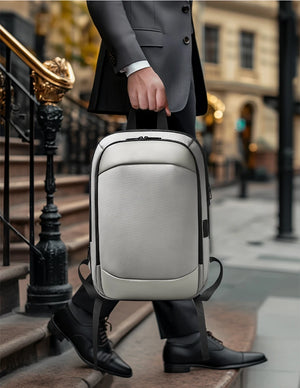 Light gray/black travel backpack standing upright with side handle and straps