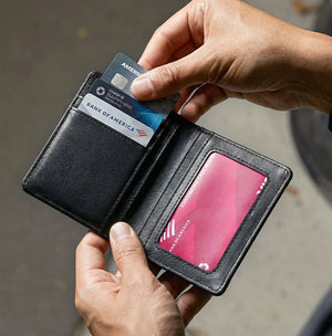 Black bifold wallet open with credit cards in card slots, textured lining.