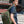 Green backpack worn by person in side profile, with brown front strap and buckles