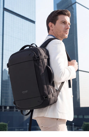 Black expandable waterproof backpack on person, side profile with adjustable straps